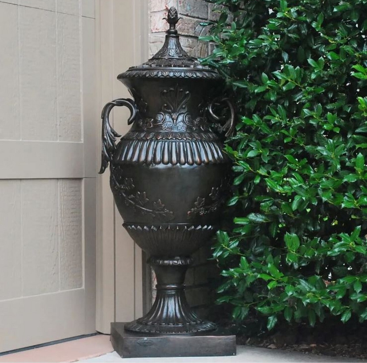 This pair of elegant bronze floor urns with a lid features decorative handles and ornate floral and leaf elements that are sure to make a statement anywhere you display them.
