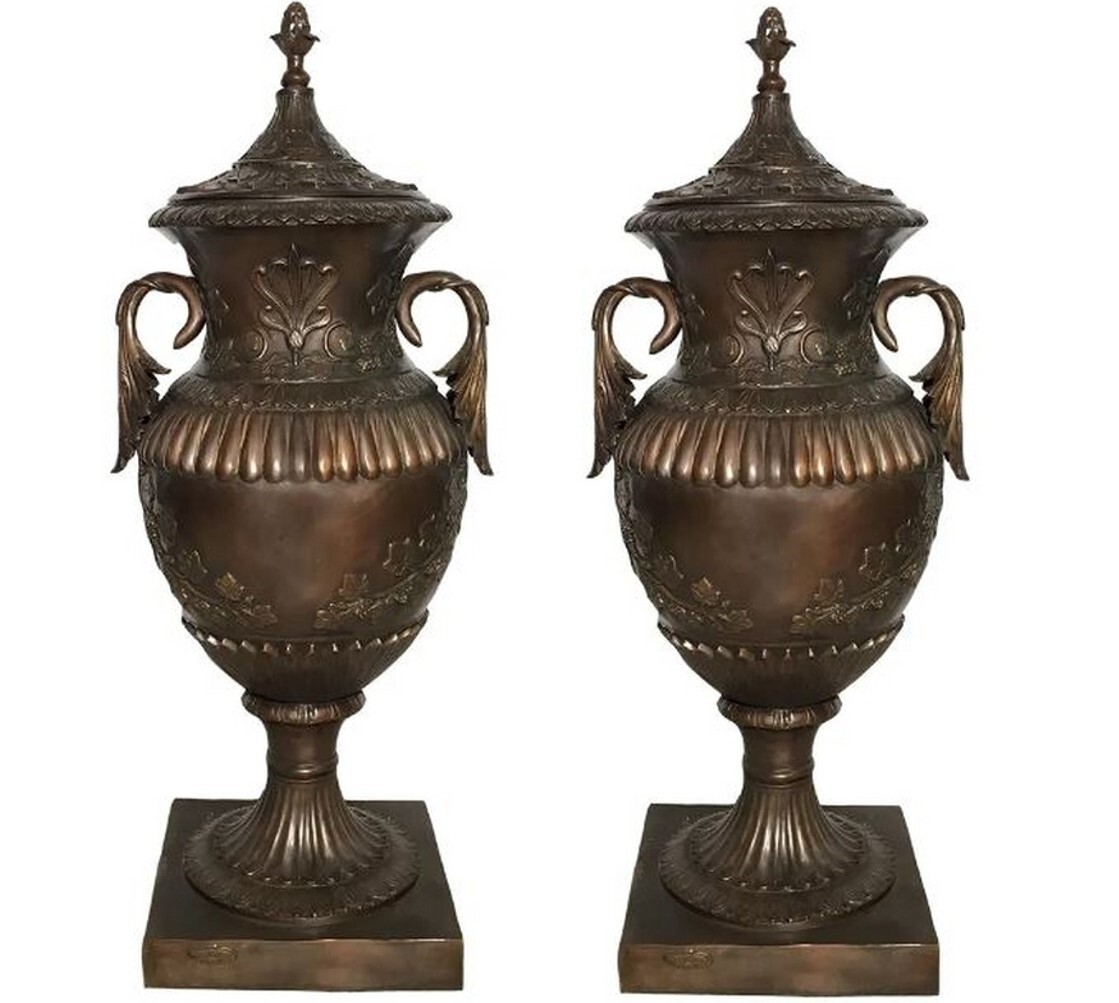 This pair of elegant bronze floor urns with a lid features decorative handles and ornate floral and leaf elements that are sure to make a statement anywhere you display them. They are perfect for indoor or outdoor.