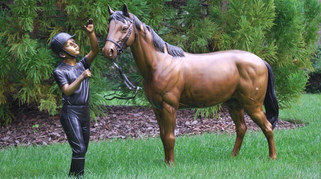 Bronze Girl Jockey with Pony Sculpture: A Timeless Outdoor Statement This highly-detailed bronze outdoor sculpture set features a young girl jockey with her pony.