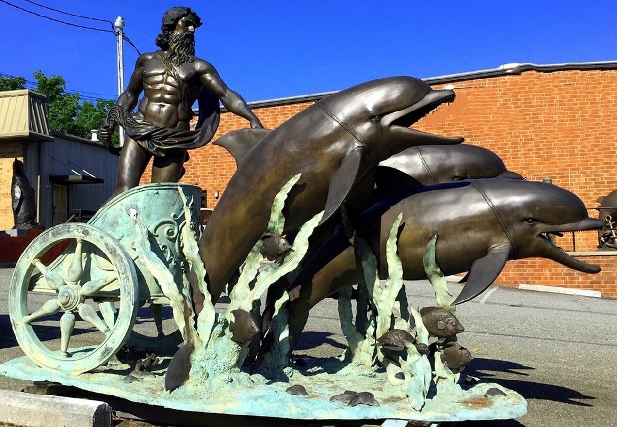 This larger-than-life bronze fountain sculpture features the mythological Roman god Neptune riding a chariot led by dolphins.